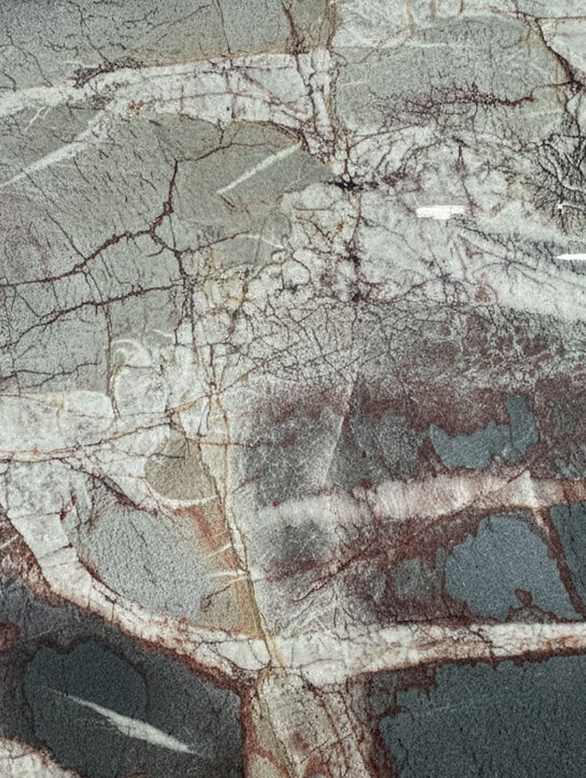 Vittra, close-up of a grey-green slab crossed by pale bands and a web of rust-red veins